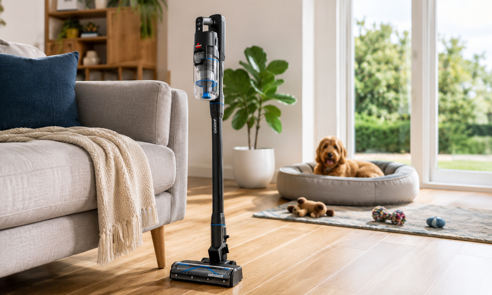 BISSELL PowerClean FurGuard 280W self-standing cordless vacuum standing upright on timber flooring in a bright Australian living room with a sofa, dog bed, pet toys, and natural daylight.